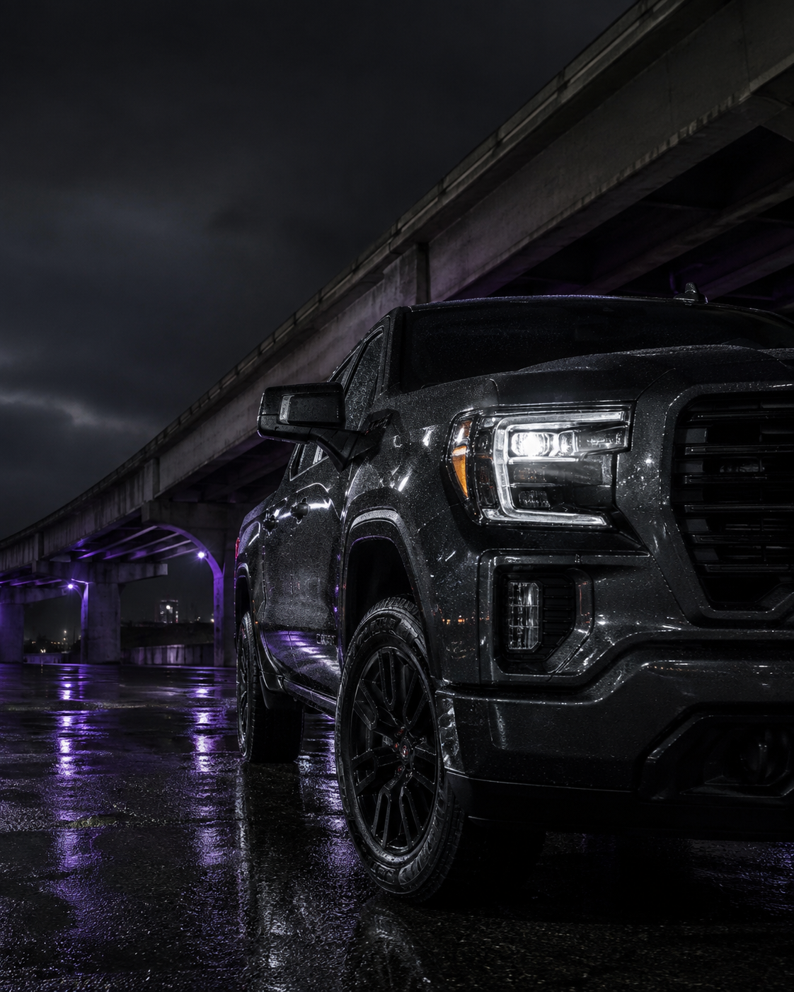 Dark pickup truck beneath a Houston overpass at night